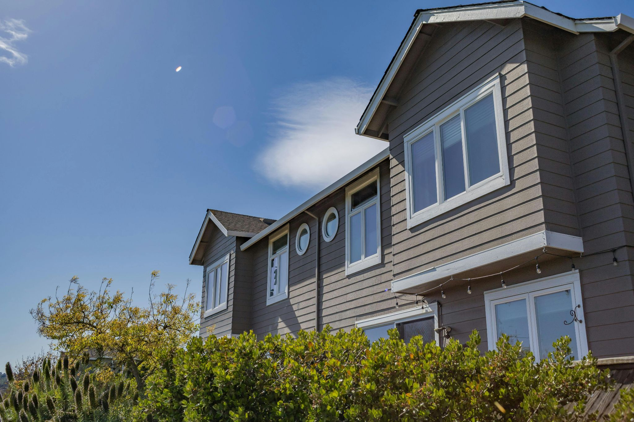 Duplex exterior with blue sky in background and hedge in foreground.